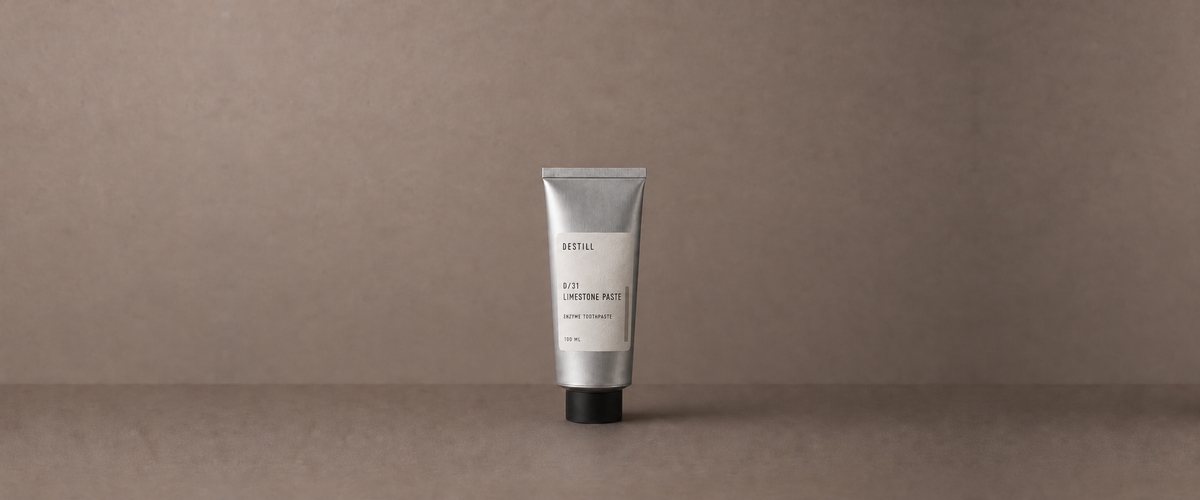 Limestone Paste enzyme toothpaste by DESTILL on a warm mineral clay background